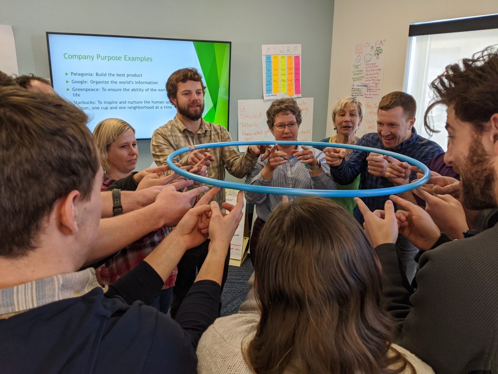 Team gathered around a ring held up by individuals in a circle.