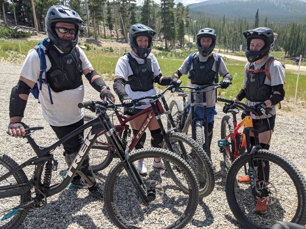 360 Engineering team members gathered on a mountain bike trail in helmets and protective gear.