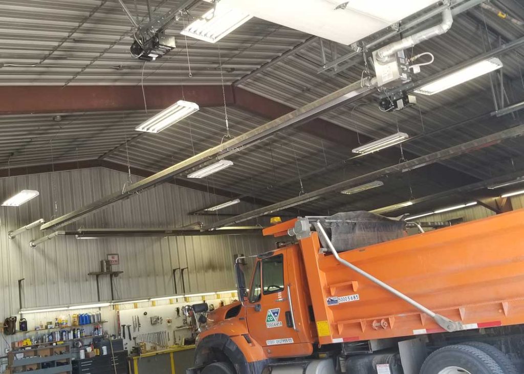 Interior of CDOT maintenance garage with orange dump truck and HVAC systems by 360 Engineering mounted from the ceiling.